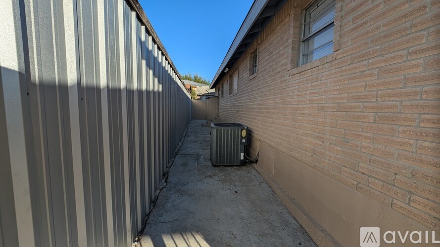 A metal wall and a brick wall meet in the middle of a concrete walkway.
