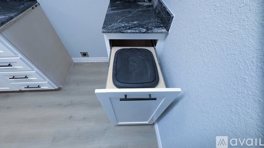 A small white cabinet with a black top is mounted on a wall.