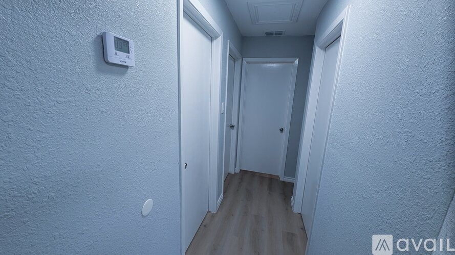 A hallway with a door on the right and a wall-mounted thermostat on the left.