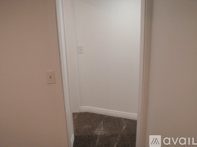 A hallway with a carpeted floor and white walls.