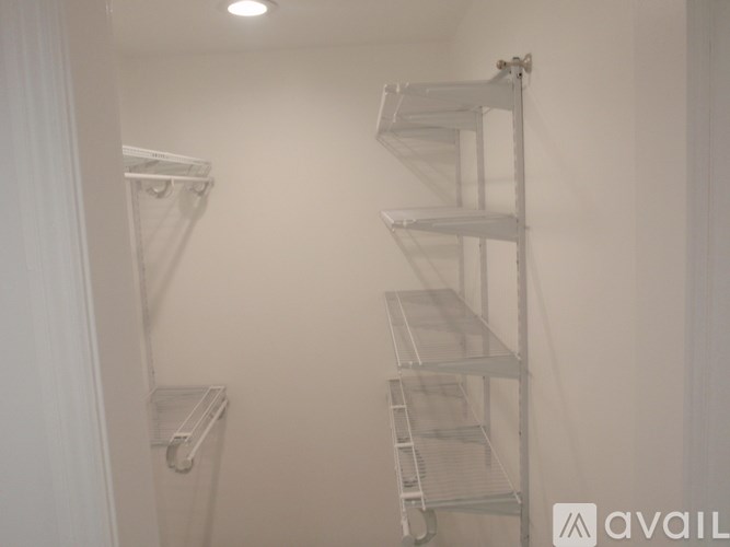 A white shelving unit with three shelves is mounted on a white wall.