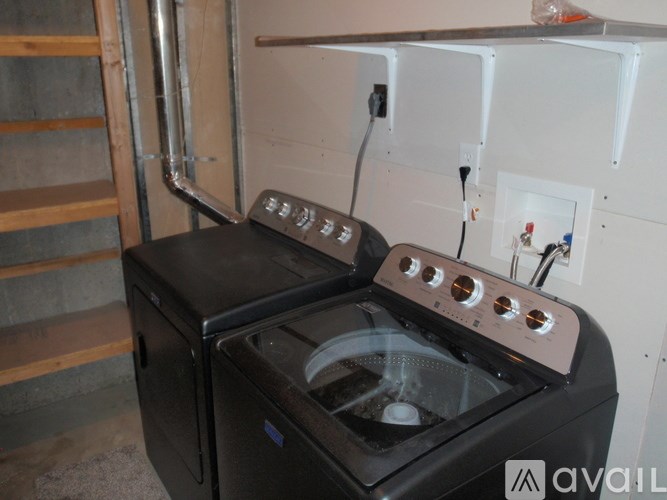 A black oven with a stove on top is in a room with a white wall and a pipe.
