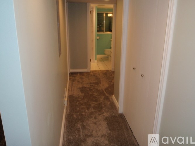 A hallway with a carpeted floor and a doorway leading to a bathroom.