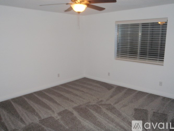 A room with a ceiling fan and a window with blinds.