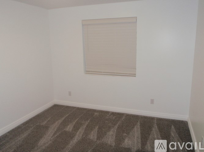 A room with a carpeted floor and a window with blinds.