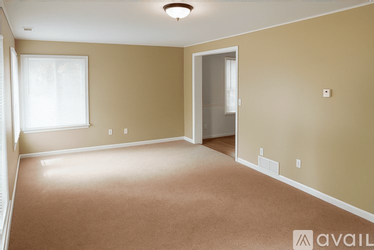 A spacious room with beige walls and carpeted floor.