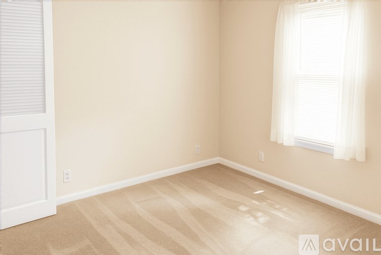 A room with a window and a carpeted floor.
