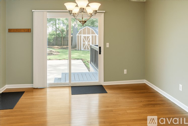 A room with wooden floors and a sliding glass door leading to a backyard.