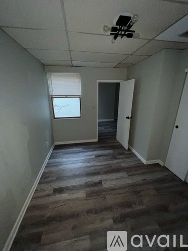 A room with a wooden floor and a window with blinds.