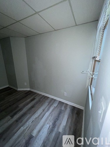 A room with wooden flooring and a white wall.