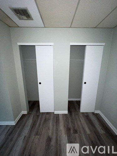 Two white doors in a room with wooden floors.