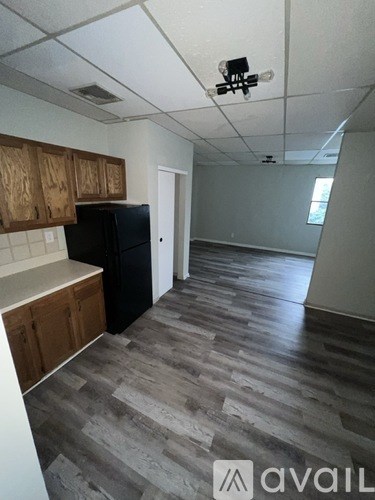 A kitchen with wooden cabinets and a black fridge.
