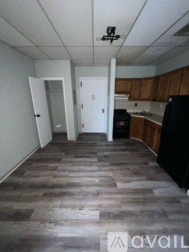 A kitchen with a black fridge and wooden cabinets.