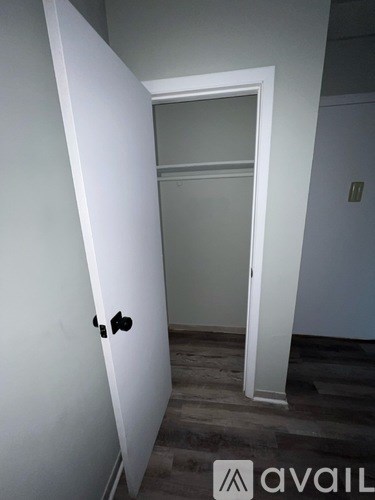 A white door with a black handle is open to a room with a grey wall.