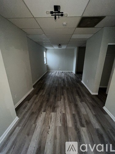 A long empty room with wooden floors and white walls.