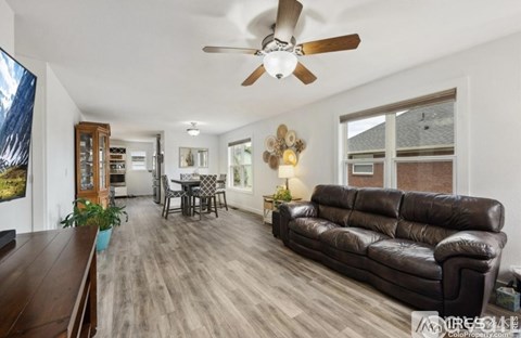 A living room with a black leather couch and a ceiling fan.