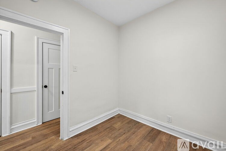 A room with a white door and wooden flooring.