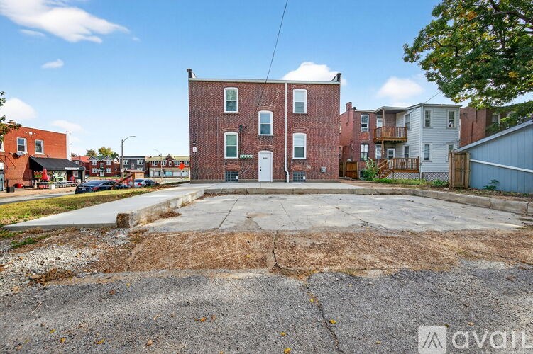 A red brick building with a white door in the middle of a parking lot.