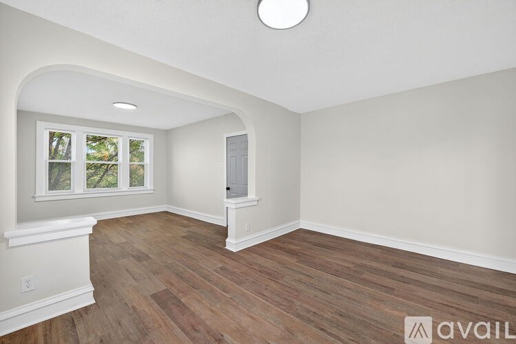 A room with wooden flooring and a window with a view of trees.