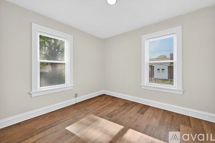 A room with two windows and wooden flooring.