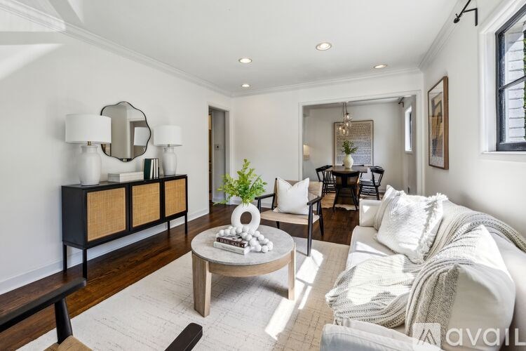 A living room with a white couch, a wooden coffee table, and a mirror on the wall.