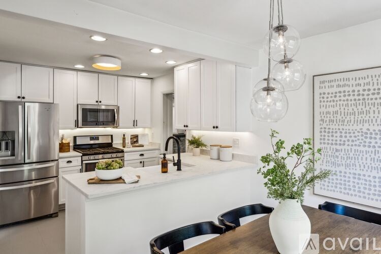 A modern kitchen with a white countertop and stainless steel appliances.