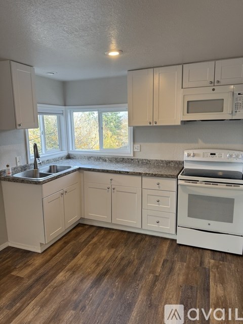 A kitchen with white cabinets and a wooden floor.