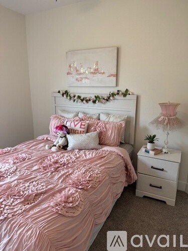 A bedroom with a pink bedspread and a white bed.