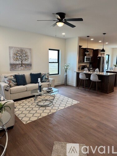 A living room with a white couch and a painting of a tree on the wall.