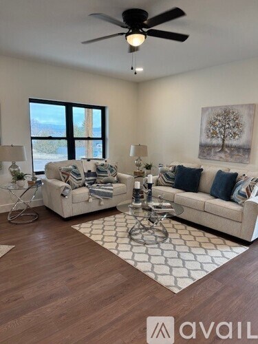 A living room with a white couch and a painting of a tree on the wall.