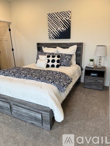 A bedroom with a bed, nightstand, and lamp.