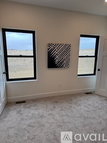 A room with two windows and a painting on the wall.