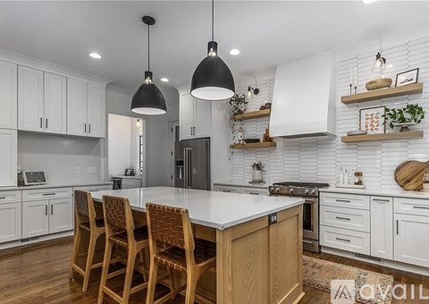A kitchen with white cabinets and a wooden island.
