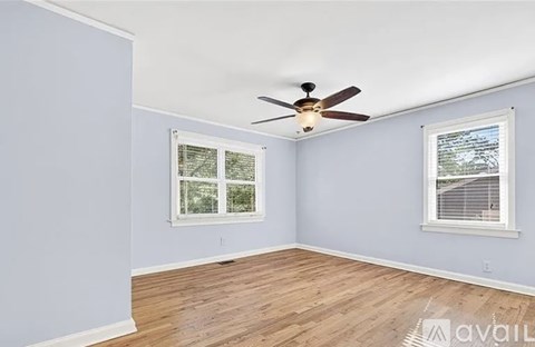 A room with a ceiling fan and two windows.