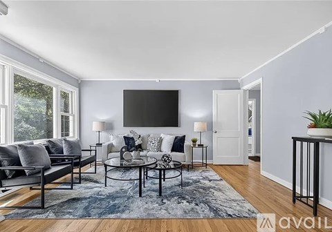A living room with a grey sofa, a black coffee table, and a flat screen TV mounted on the wall.