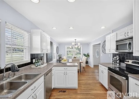 A modern kitchen with white cabinets and stainless steel appliances.