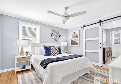 A bedroom with a white bed and a ceiling fan.