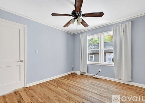A room with a ceiling fan and a window with curtains.