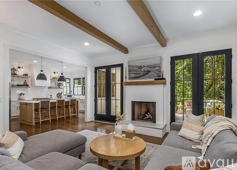 A modern living room with a fireplace and a dining area in the background.