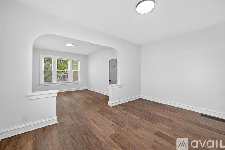 A room with wooden flooring and a window showing greenery outside.