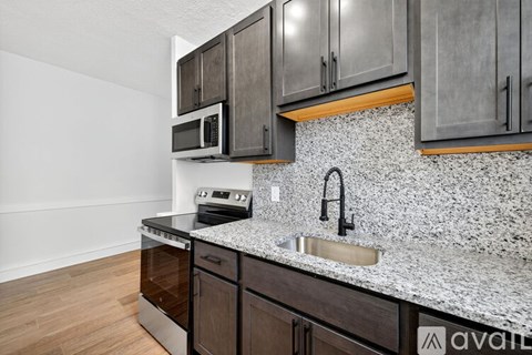 A kitchen with dark wood cabinets and a granite countertop.