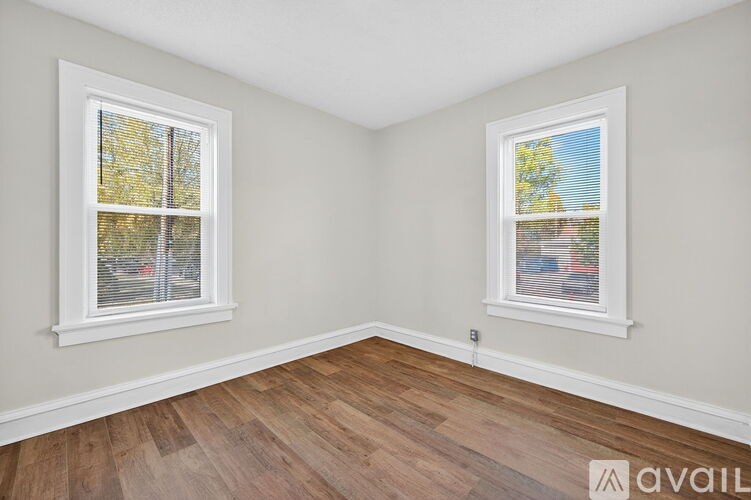 A room with two windows and wooden flooring.