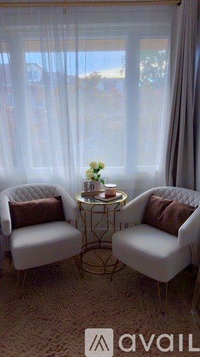 Two white chairs with a small table between them.