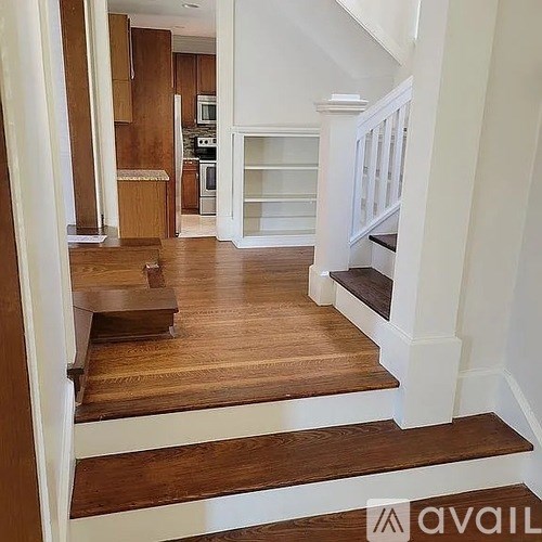 A wooden staircase with white railings leads to a second floor.