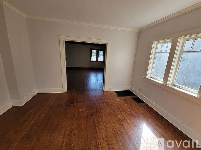 A room with wooden flooring and a window on the right side.