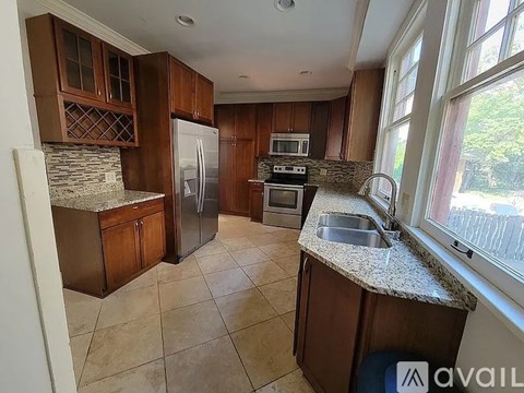 A kitchen with brown cabinets and a stone backsplash.