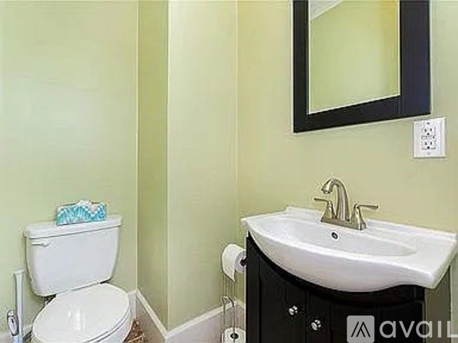A bathroom with a toilet, sink, and mirror.