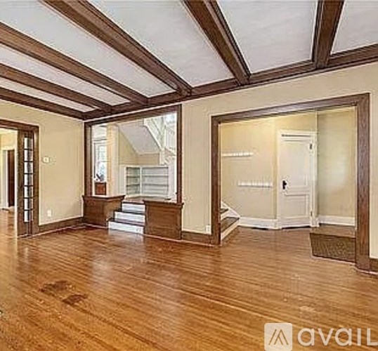 A spacious room with wooden floors and a high ceiling.