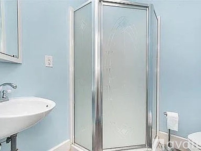 A white sink is next to a glass shower door in a blue bathroom.