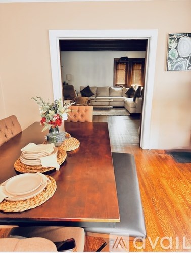 A dining table with plates and a vase of flowers on it.